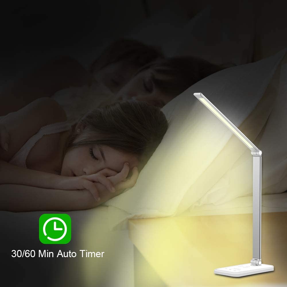 Modern LED desk lamp with wireless phone charger illuminating a minimalist office desk