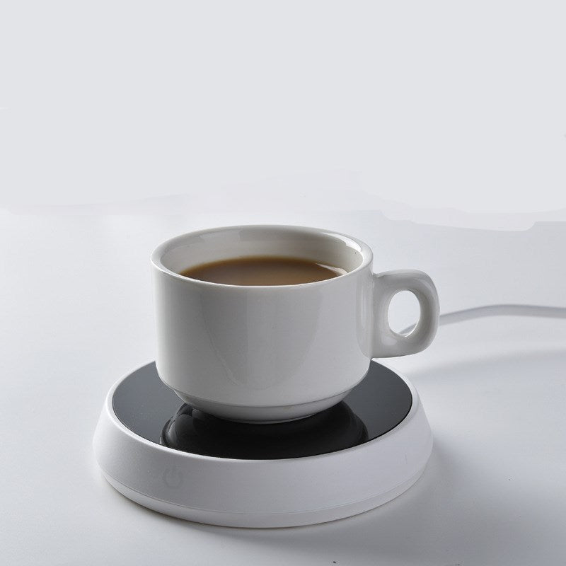Smart coffee mug warmer keeping a ceramic coffee cup at the perfect drinking temperature on an office desk